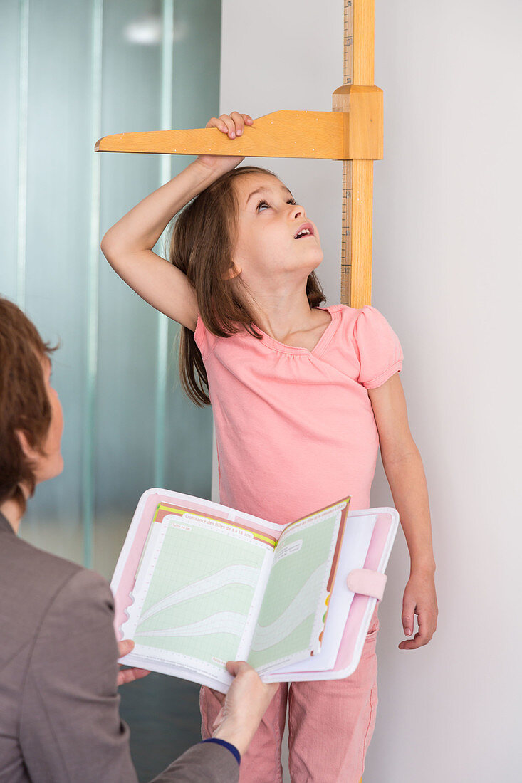 A doctor measures the height of a girl