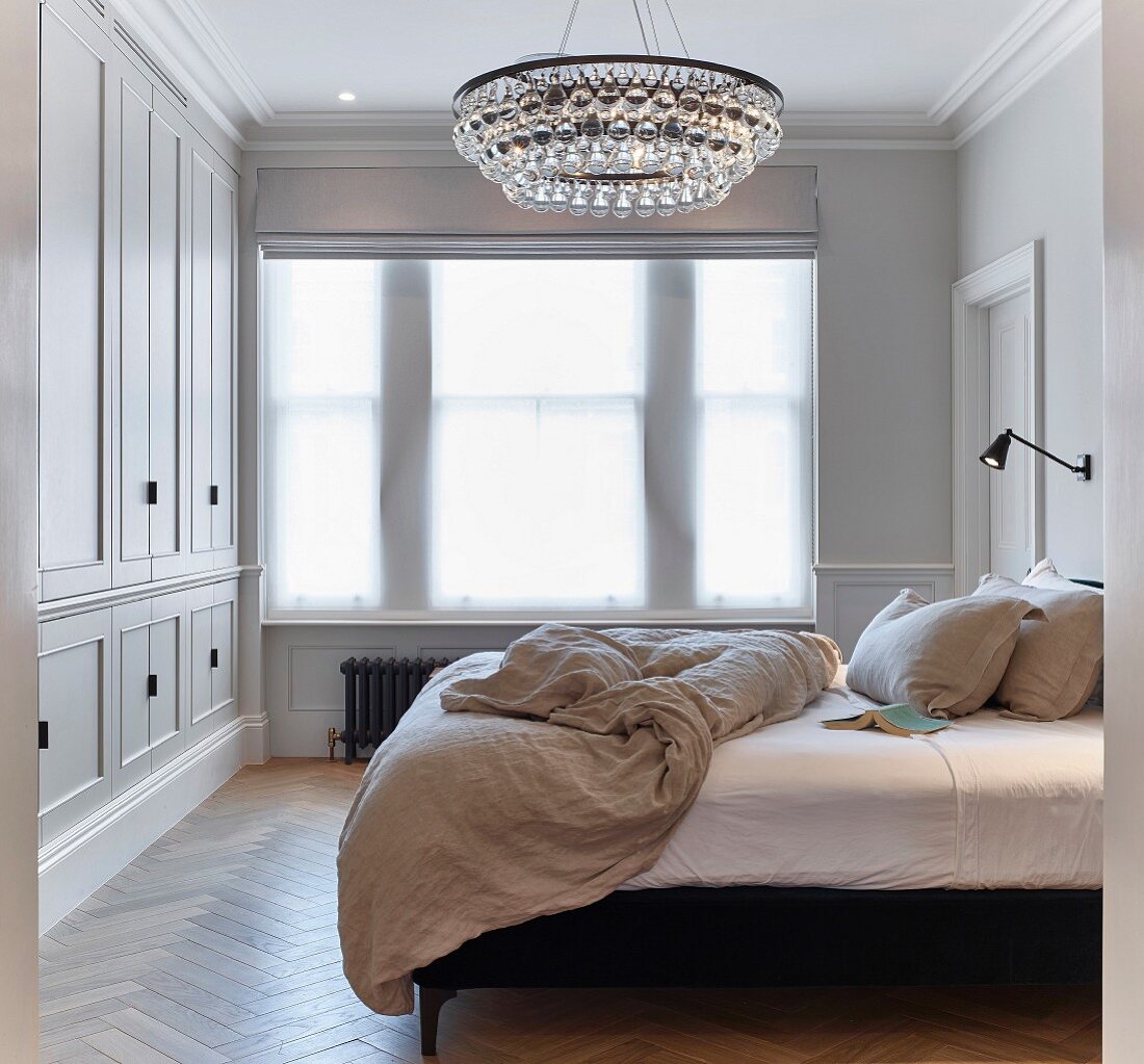 Chandelier and fitted wardrobes in elegant bedroom