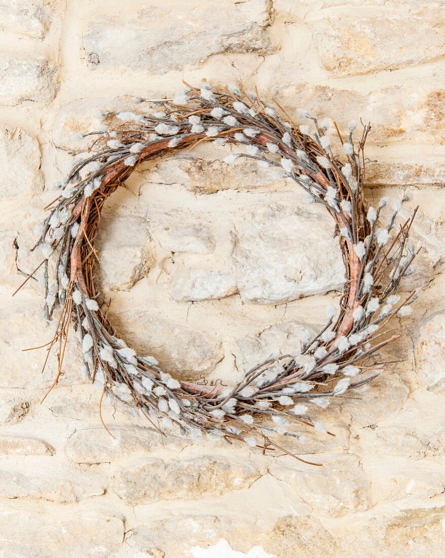 Wreath of artificial willow catkins hung on stone wall