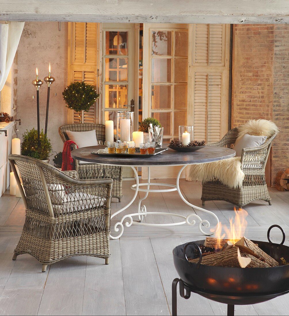 Wicker armchair at round table and fire in fire bowl