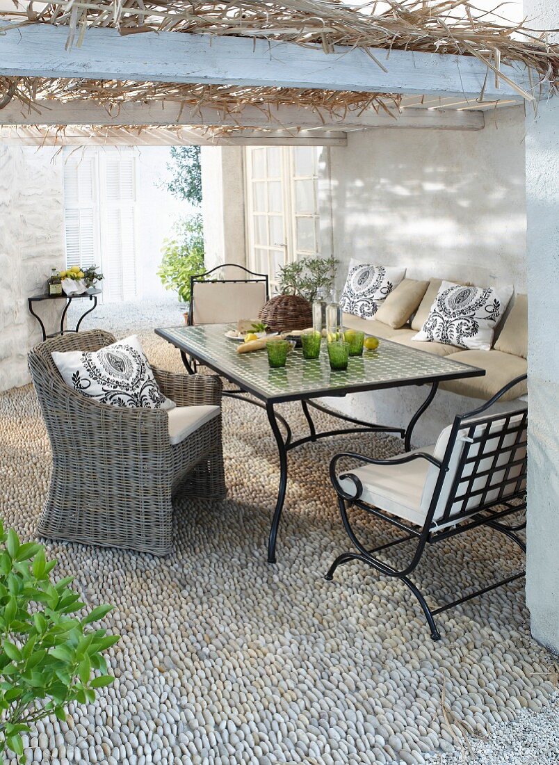 Comfortable seating area on gravel terrace below roofed pergola