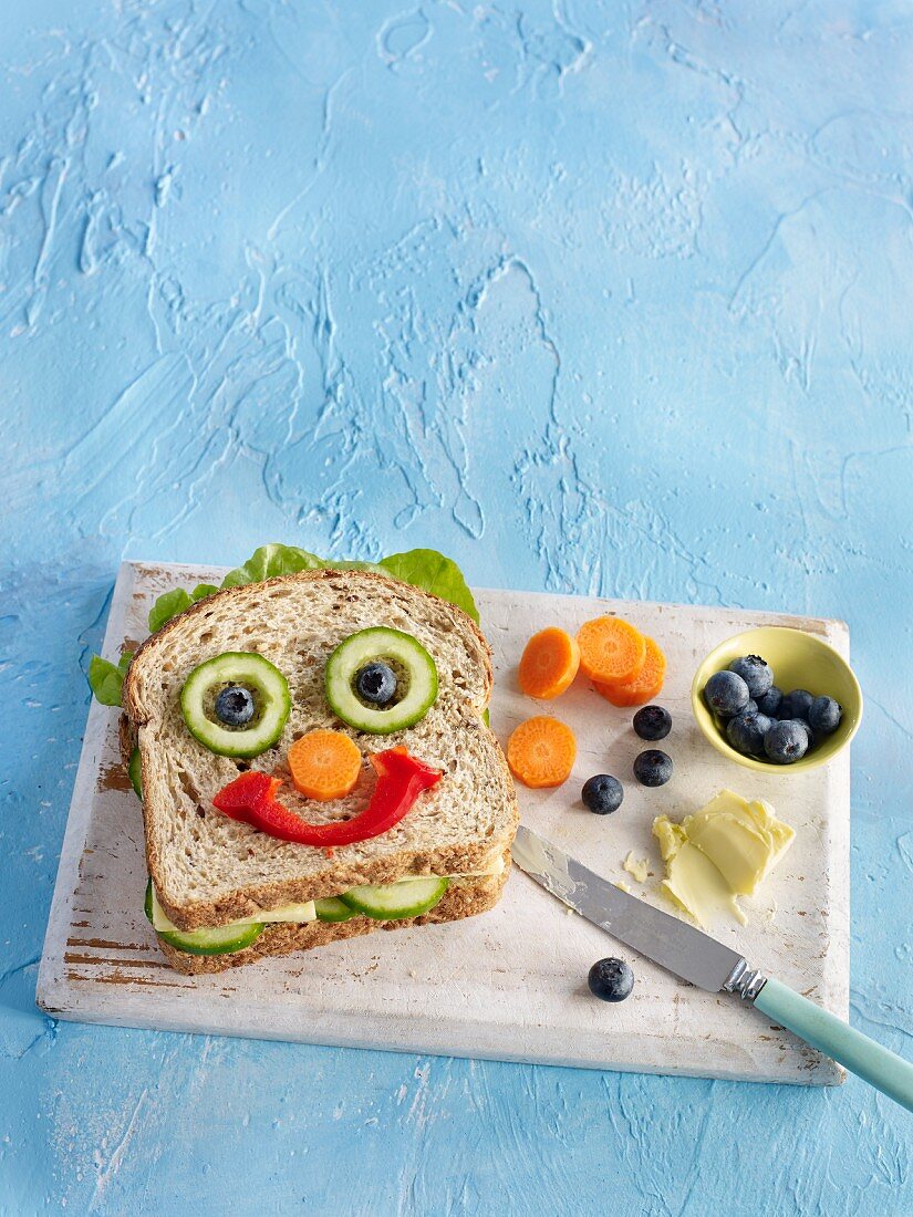A healthy sandwich with vegetables in the shape of a face