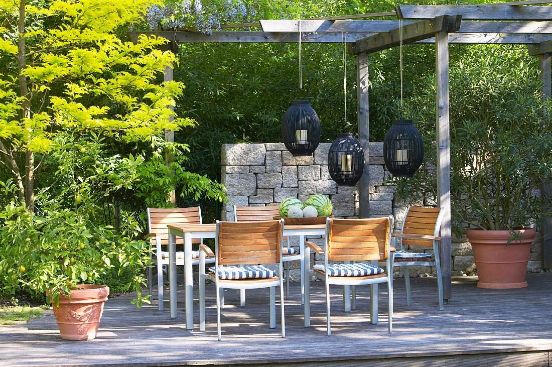 Sonniger Terrassenplatz und Holzpergola mit aufgehängten Windlichtern