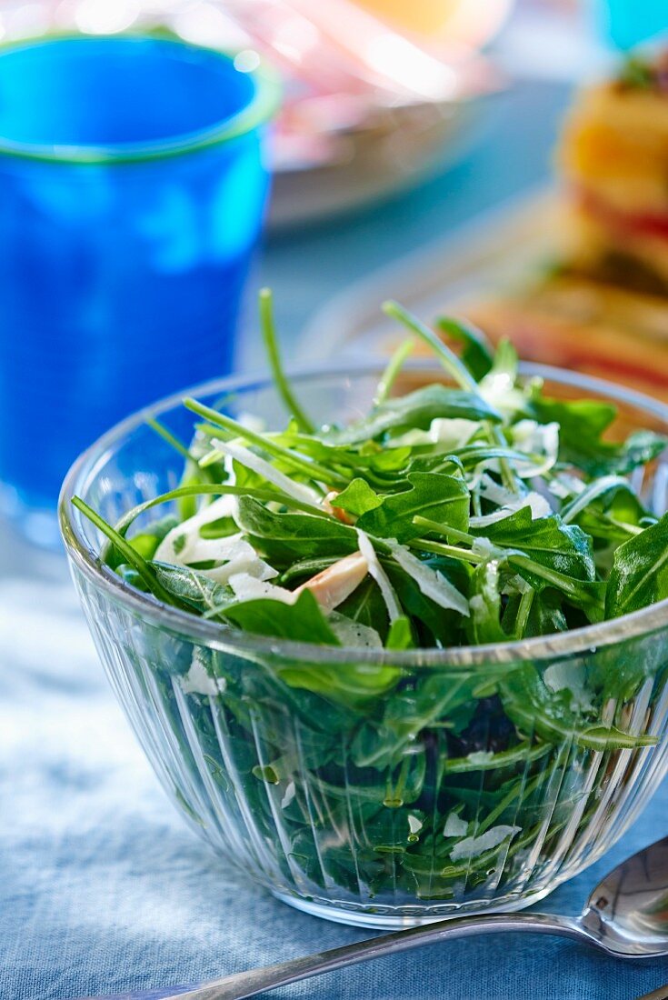 Rocket salad with parmesan in a glass bowl