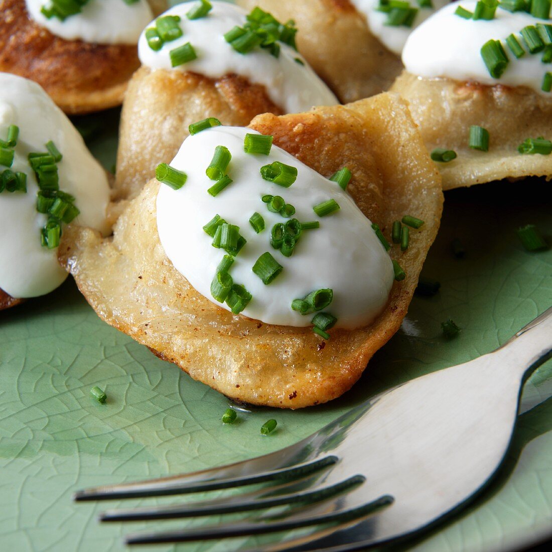 Potato filled pierogies (Pirogi) with sour cream and chives clos