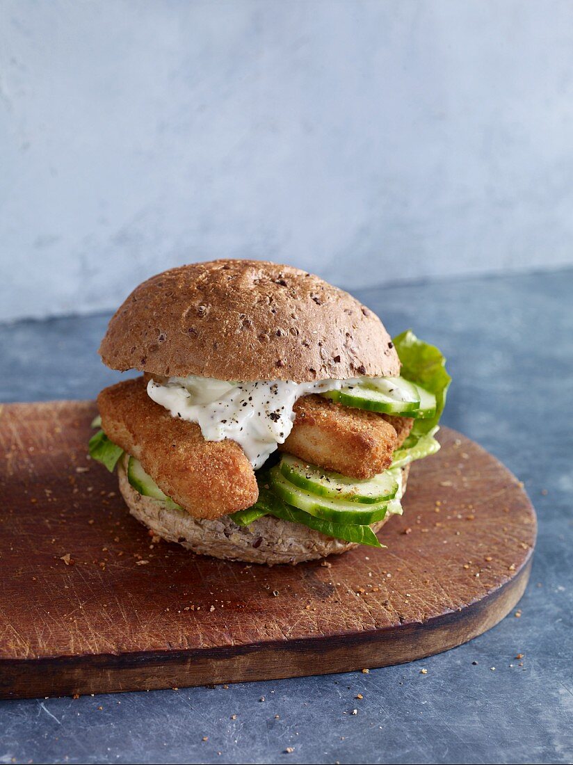 A fish finger sandwich with tartar sauce in a wholemeal bread roll
