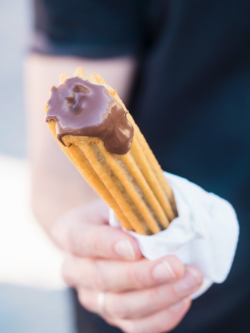 A person holding a churro in their hand