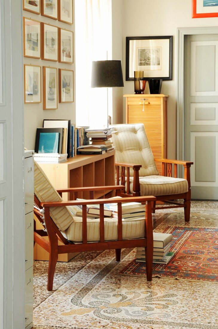 Armchairs and stacked books in lounge area in traditional interior