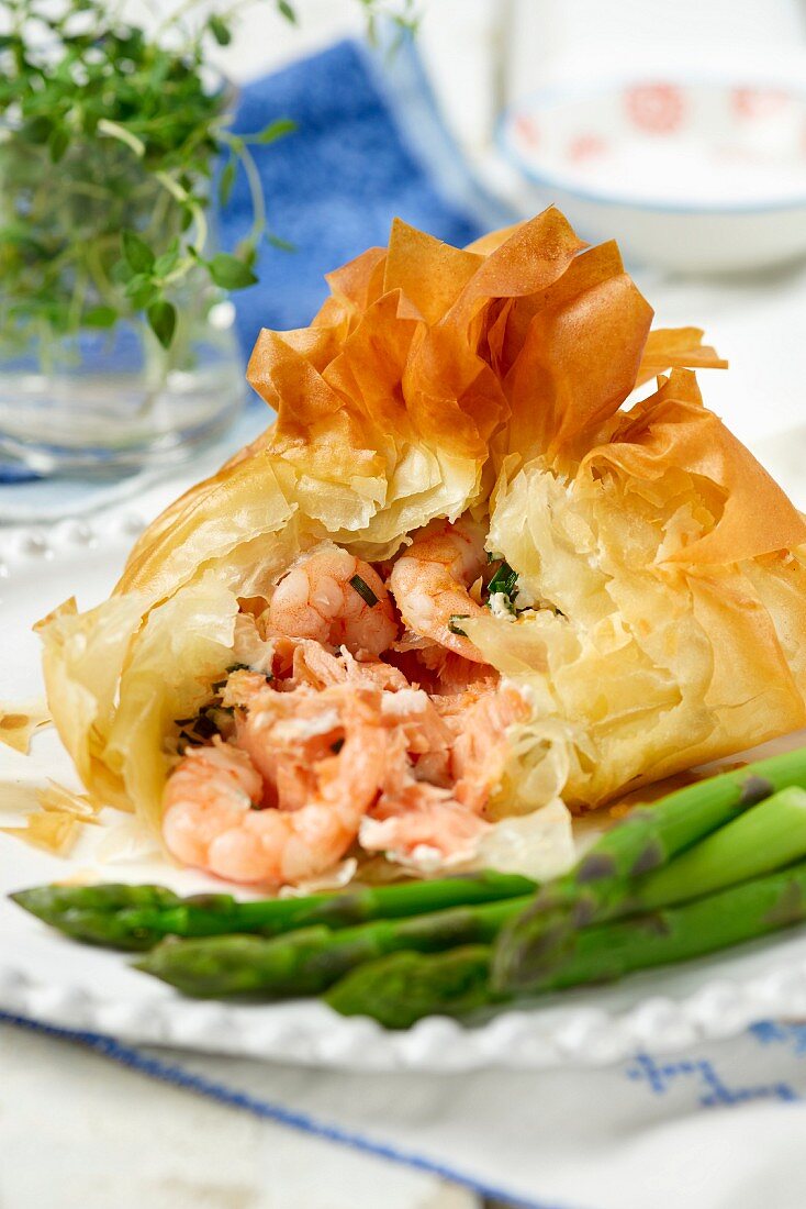 Filo pastry parcels with salmon and prawn filling and green asparagus