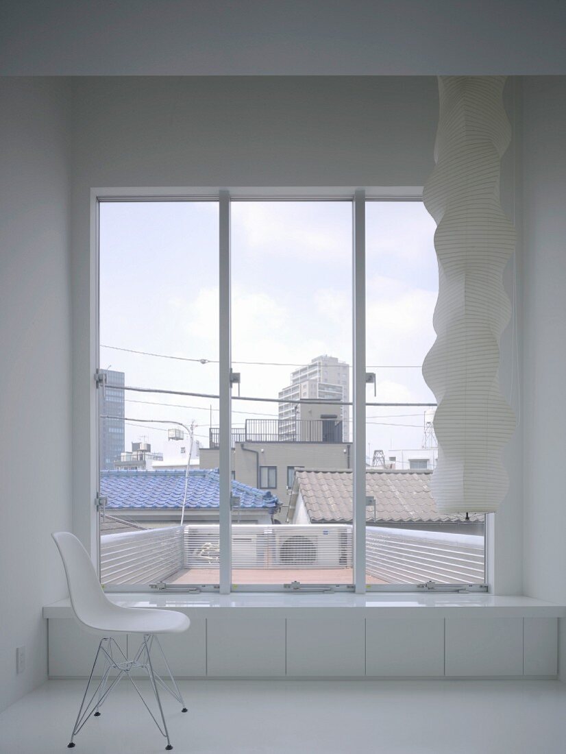 Einsamer Stuhl vor Fenster mit Blick über Dächer in Tokio, Japan