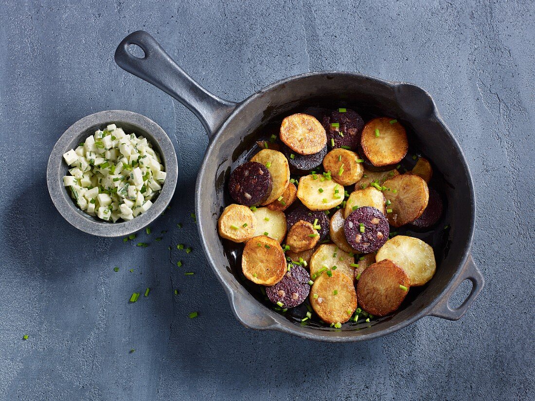 Fried potatoes and black pudding in a pan served with apple salad