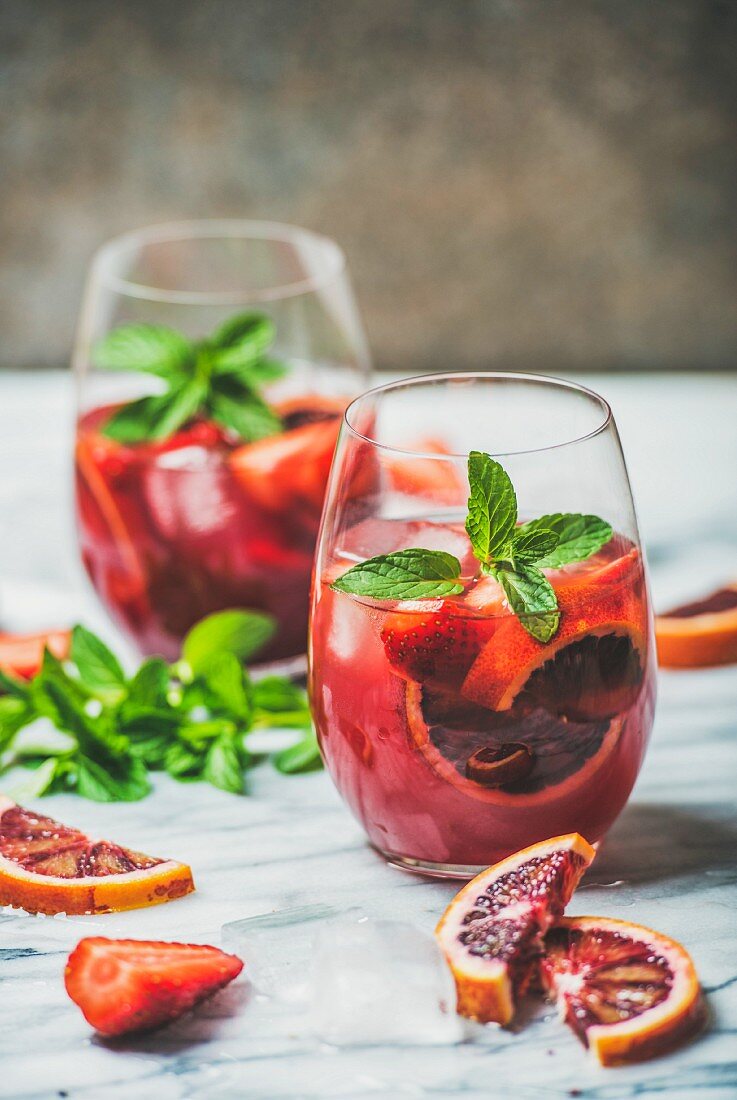 Blood orange and strawberry summer Sangria (Fruit refreshing rose wine cocktails in glasses with ice and mint leaves)