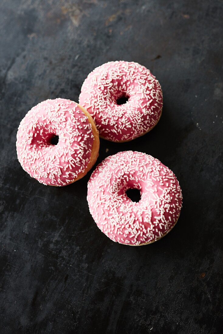 Three pink donuts with sugar sprinkles