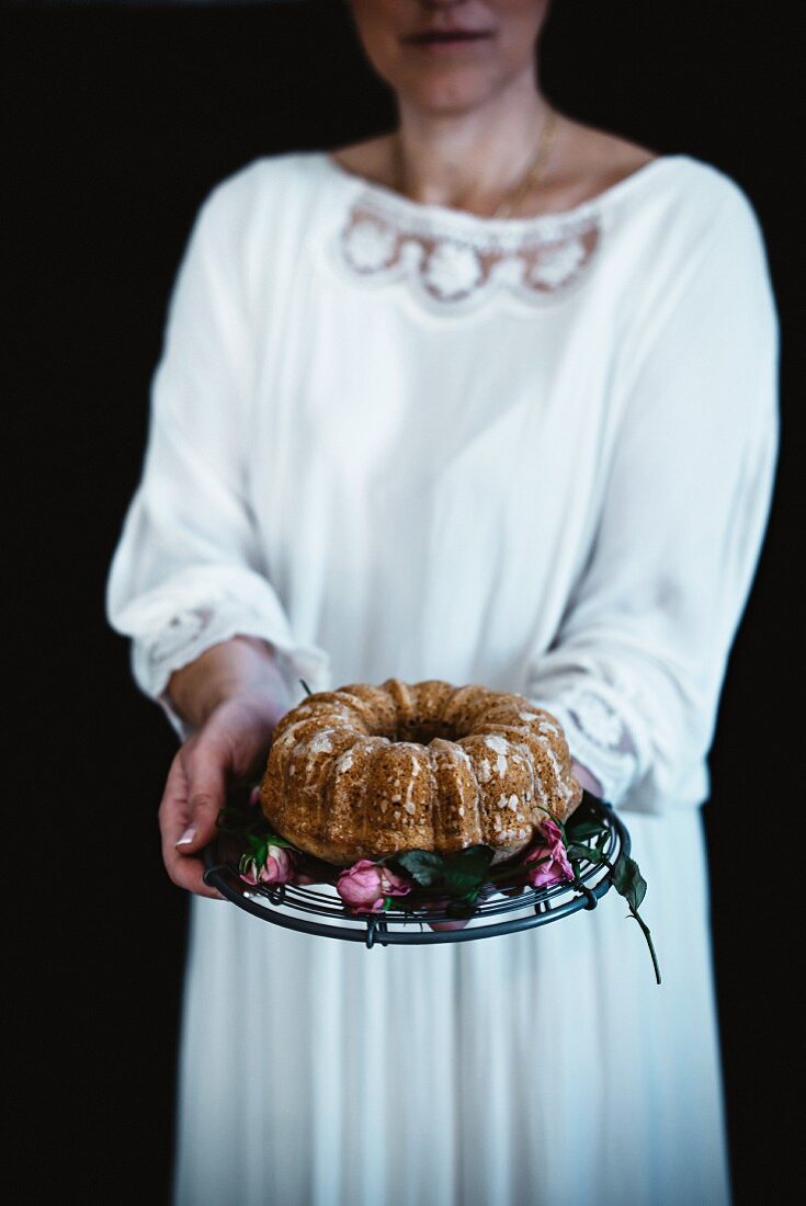 A woman holding a pear cake on a cake stand