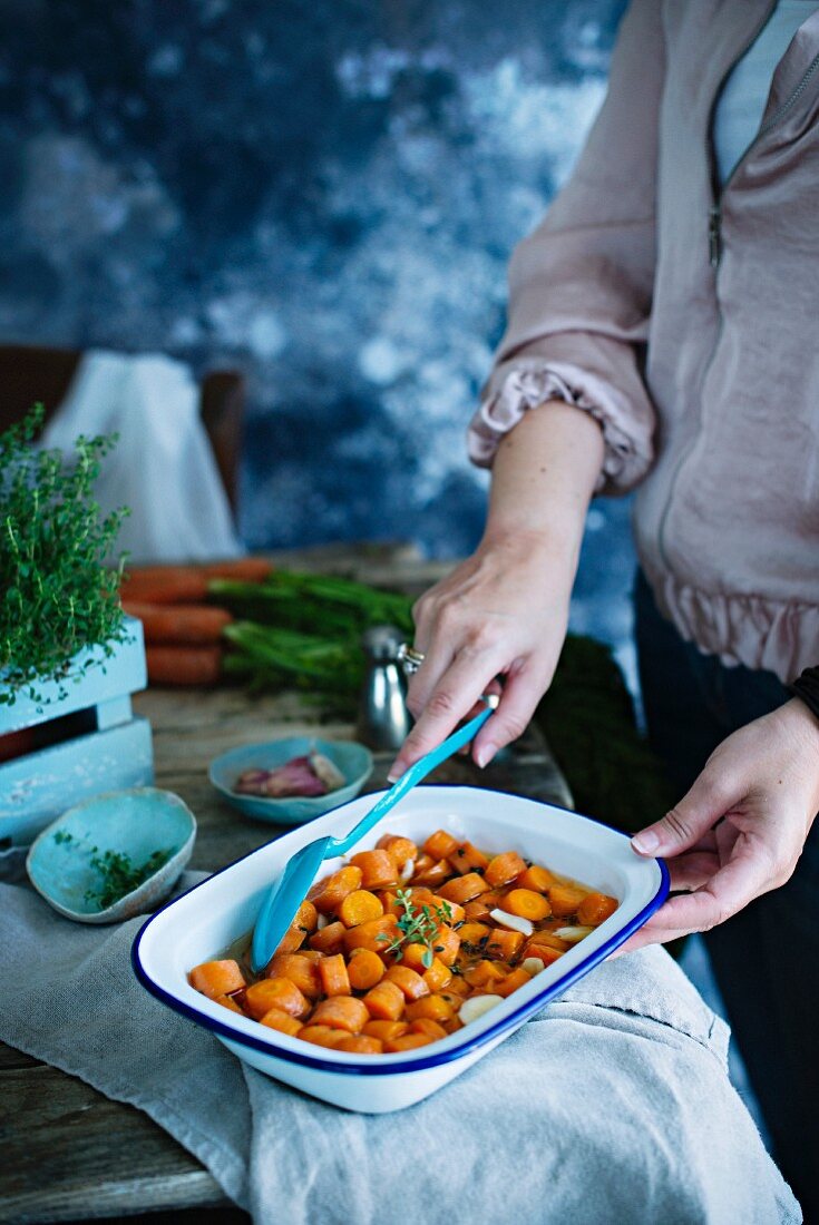 A woman cooking carrots in pan