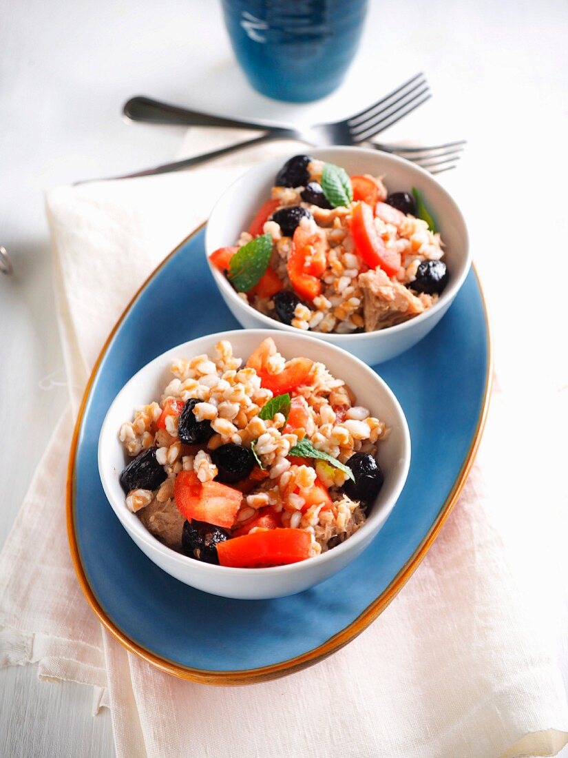 Spelt salad with canned tuna in olive oil, tomatoes, black olives and mint