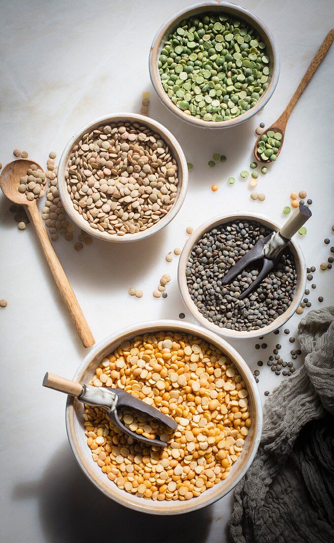 Brown lentil, French lentil, Split dry green peas and Split chana dal in individual ceramic bowls