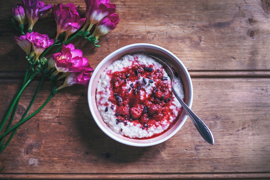 Porridge with raspberry sauce and cacao nibs in a bowl