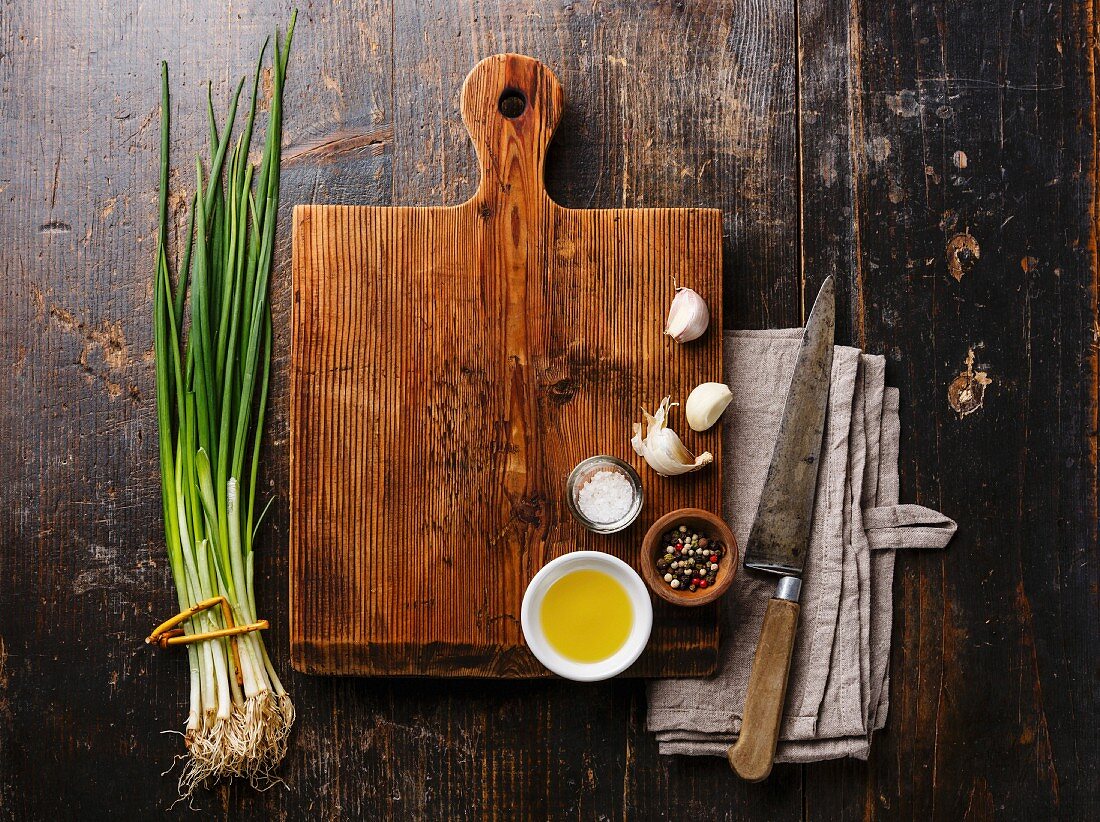 Wooden cutting board background with seasoning, herbs and kitchen knife on wooden background