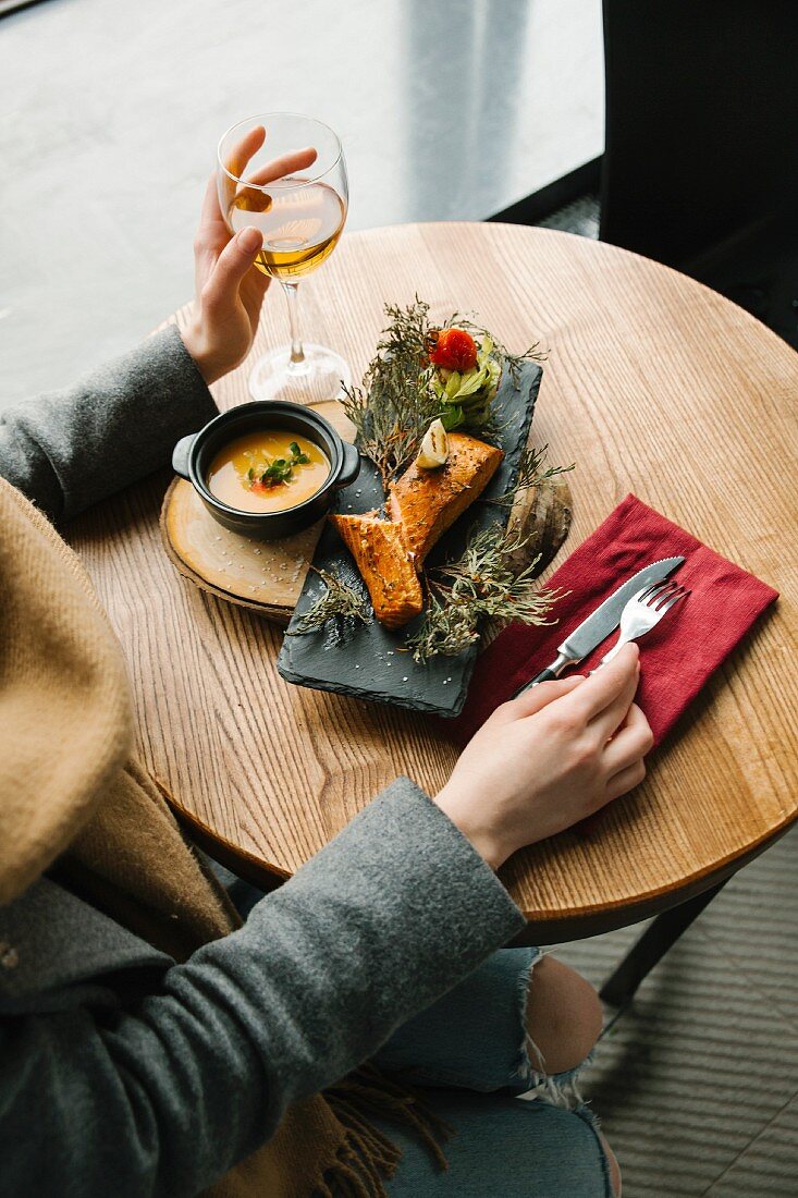 Frau isst gegrillten Lachs auf Wacholderzweigen im Restaurant