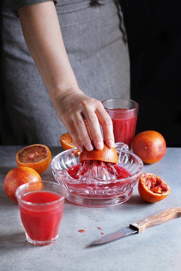 Female making blood orange juice with a citrus hand squeezer