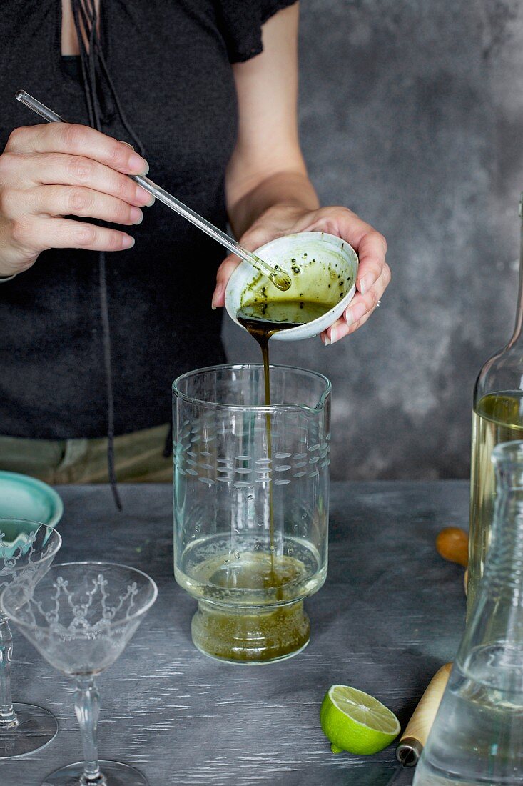 Frau bereitet Matcha-Weincocktail mit Gurkensaft zu