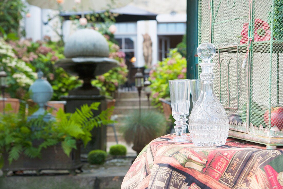 Cut-glass carafe and glasses on table in garden