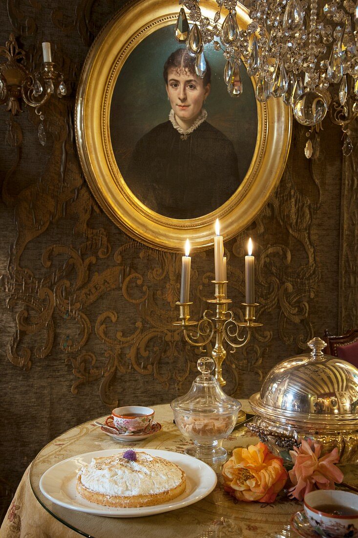Gilt-framed portrait of woman above table set in classic style
