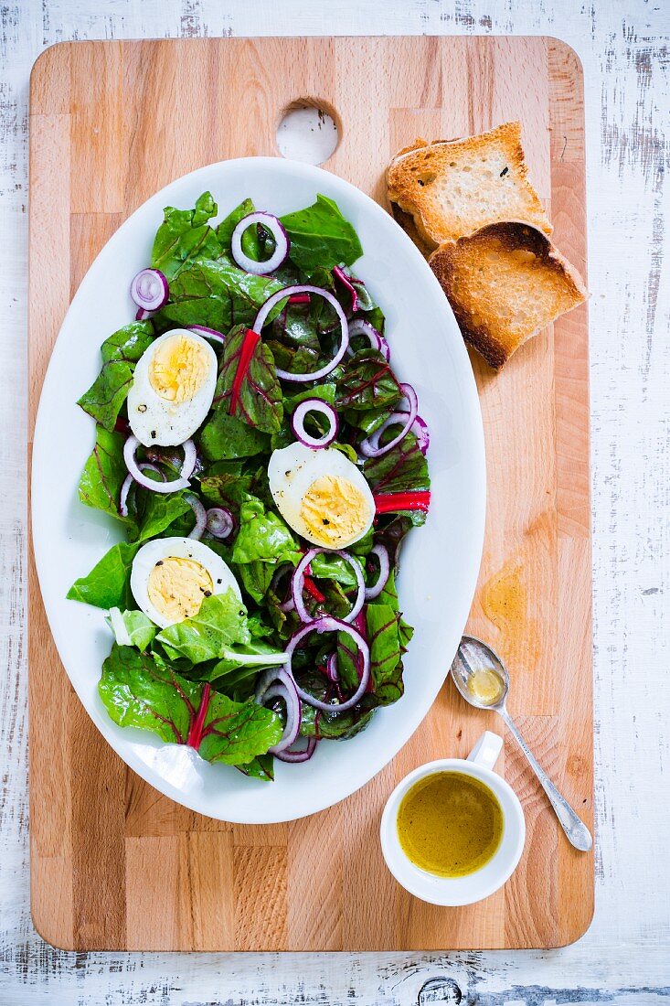 Salat mit gekochten Eiern und Vinaigrette auf Schneidebrett