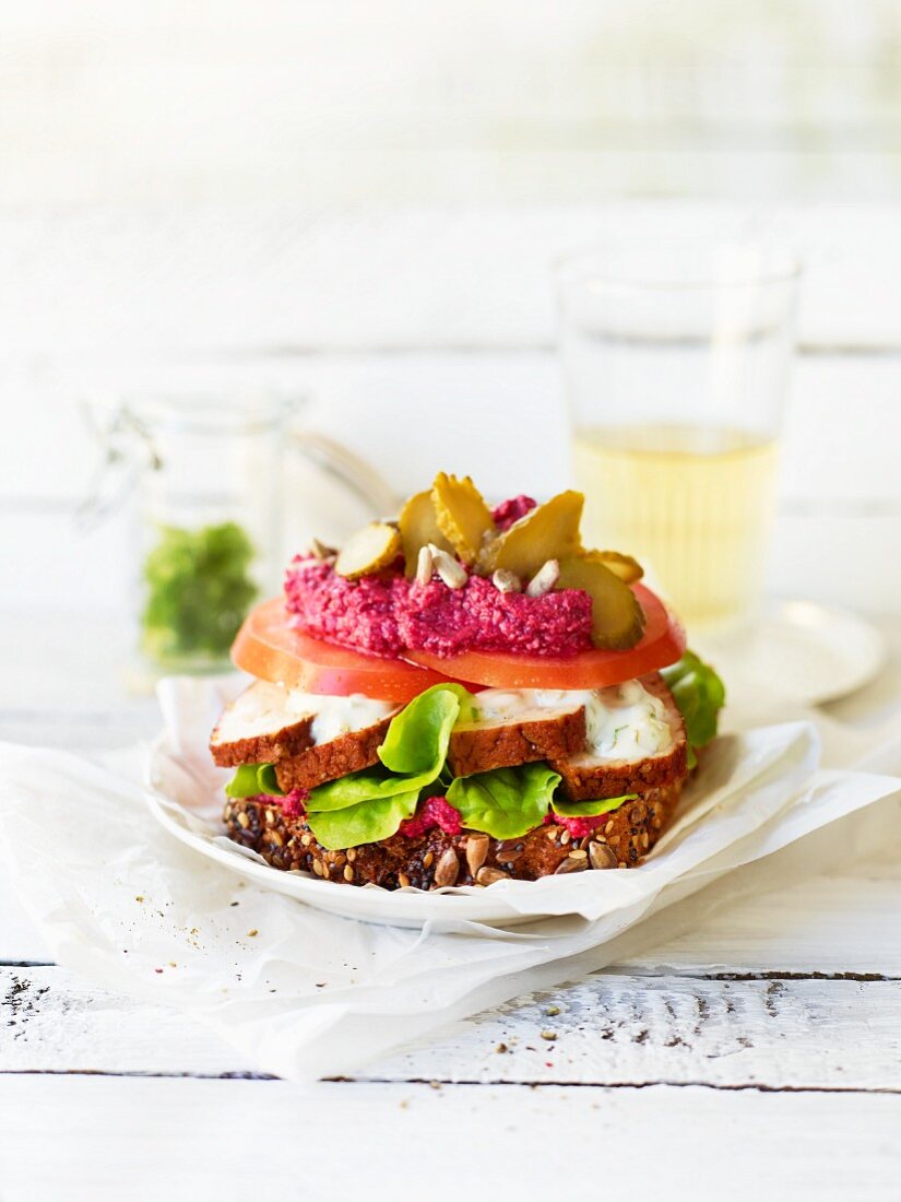 A veggie sandwich with smoked tofu, tomato, lettuce and beetroot cream