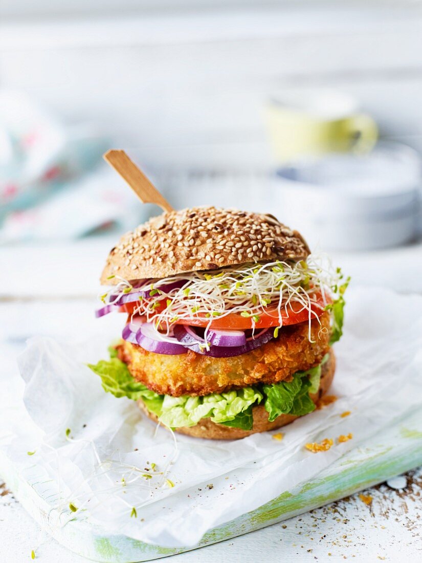 A veggie burger with sliced cabbage, lettuce, tomato and sprouts