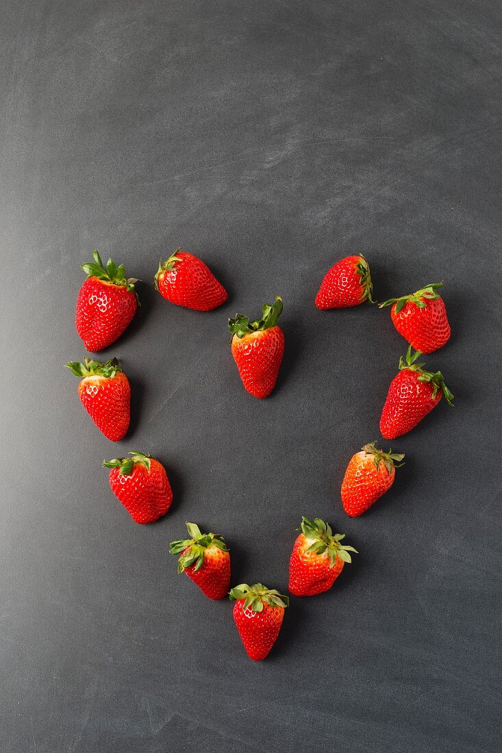 Strawberries arranged in a heart shape on a blackboard