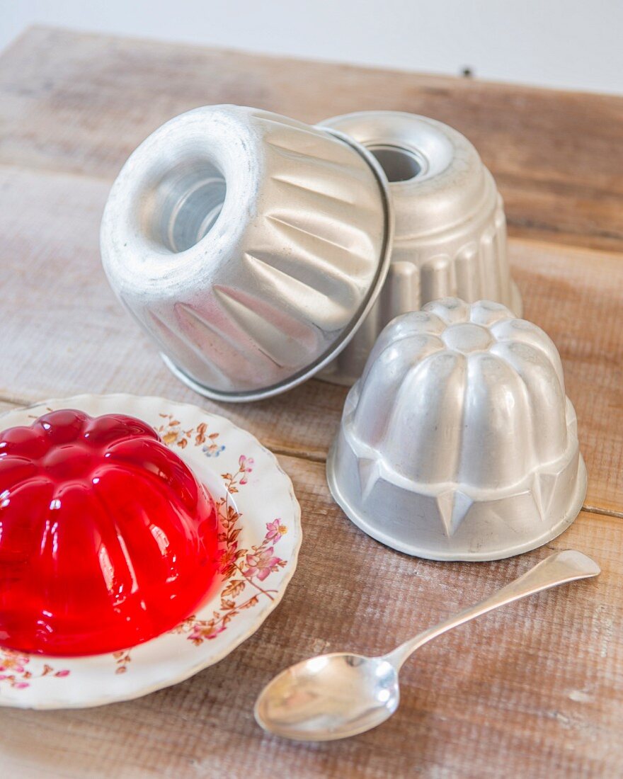 Various jelly moulds and red jelly on rustic wooden table