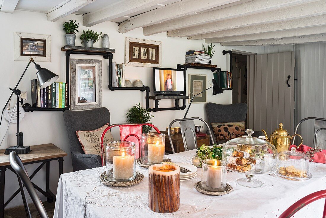 Black shelves made from piping and wooden boards and festively set dining table in cottage