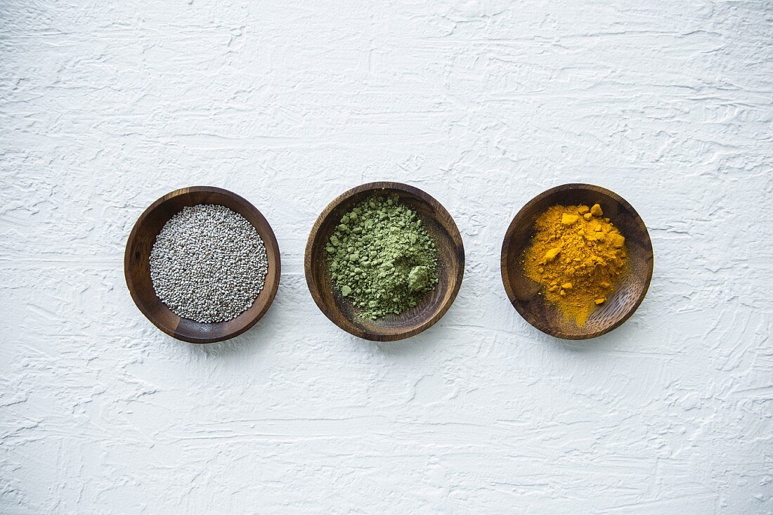 Superfood in small bowls (chia seeds, matcha powder and turmeric powder)