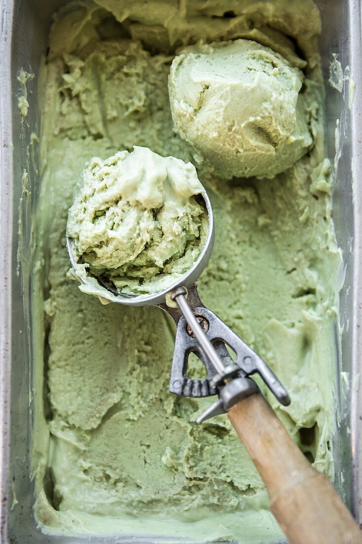 Avocado and matcha ice cream in a container with an ice cream scoop