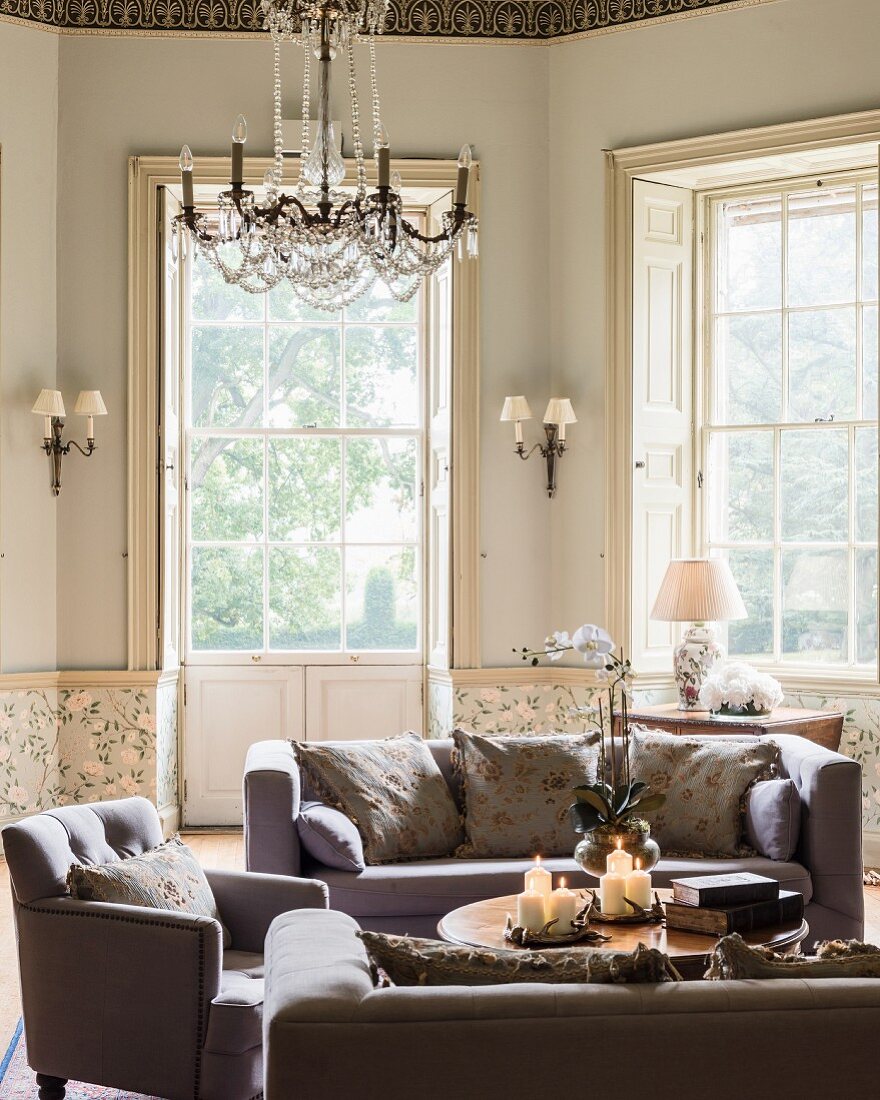 Cosy lounge with bay window, sofas, armchairs and lit candles on coffee table