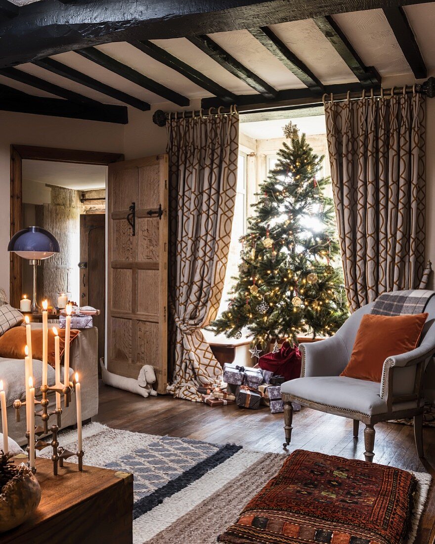 Christmas tree in living room with wood-beamed ceiling