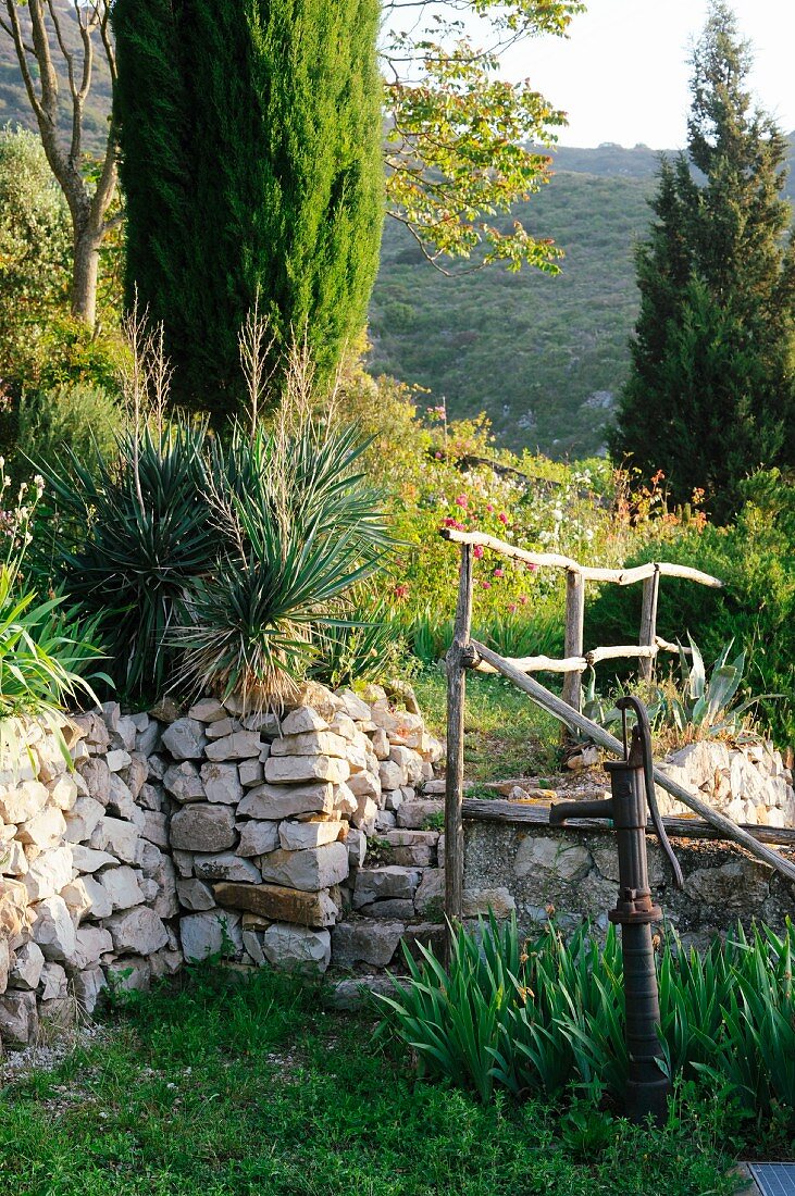 Hand pump in Mediterranean garden with stone wall