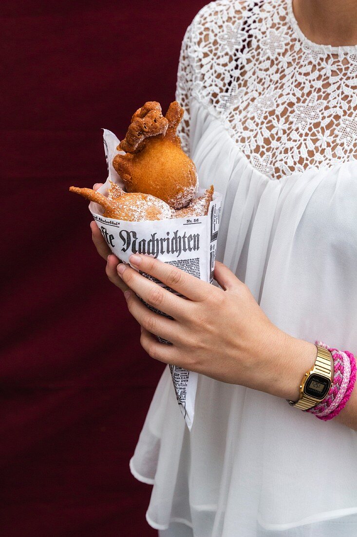 Hands of teenage girl holding paper bag of deep-fried pastries