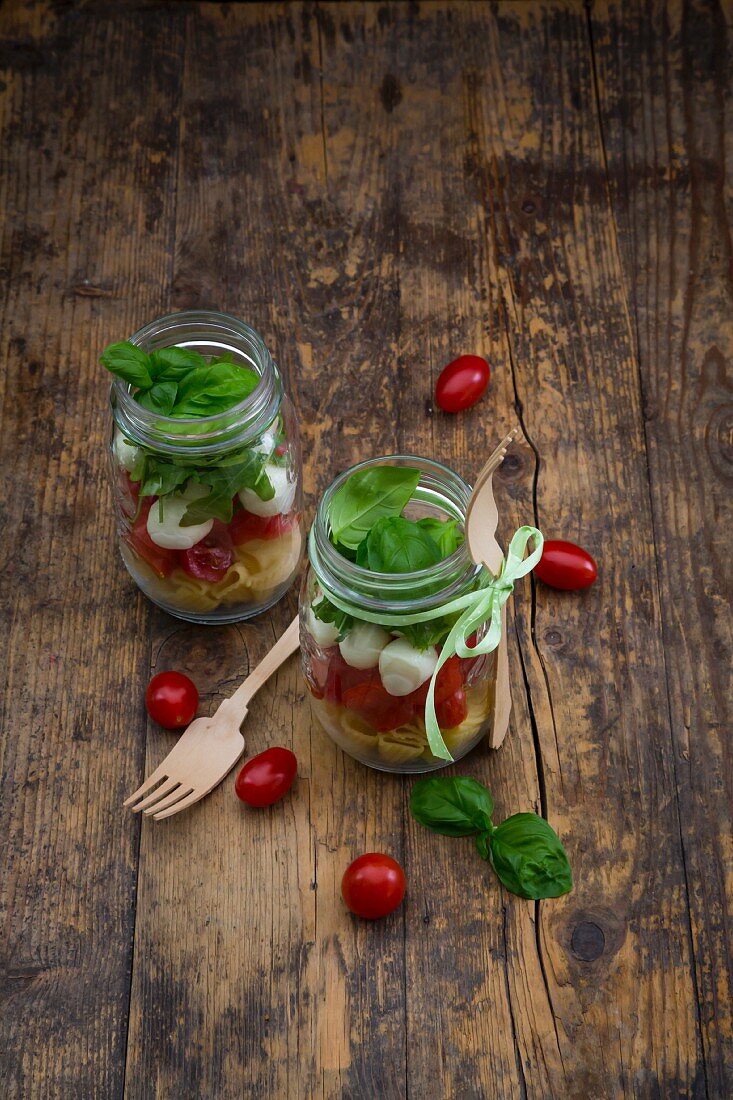 Calabrese salad with pasta, tomatoes, mozzarella, rocket and basil in glasses