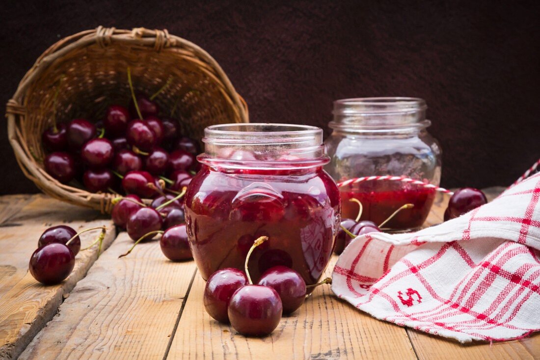 Glasses of homemade cherry groats, dish towel and cherries on wood