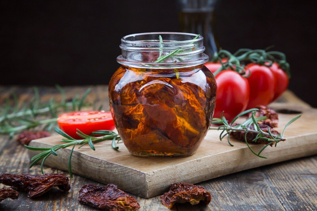 Glass of pickled dried tomatoes with rosemary, close-up