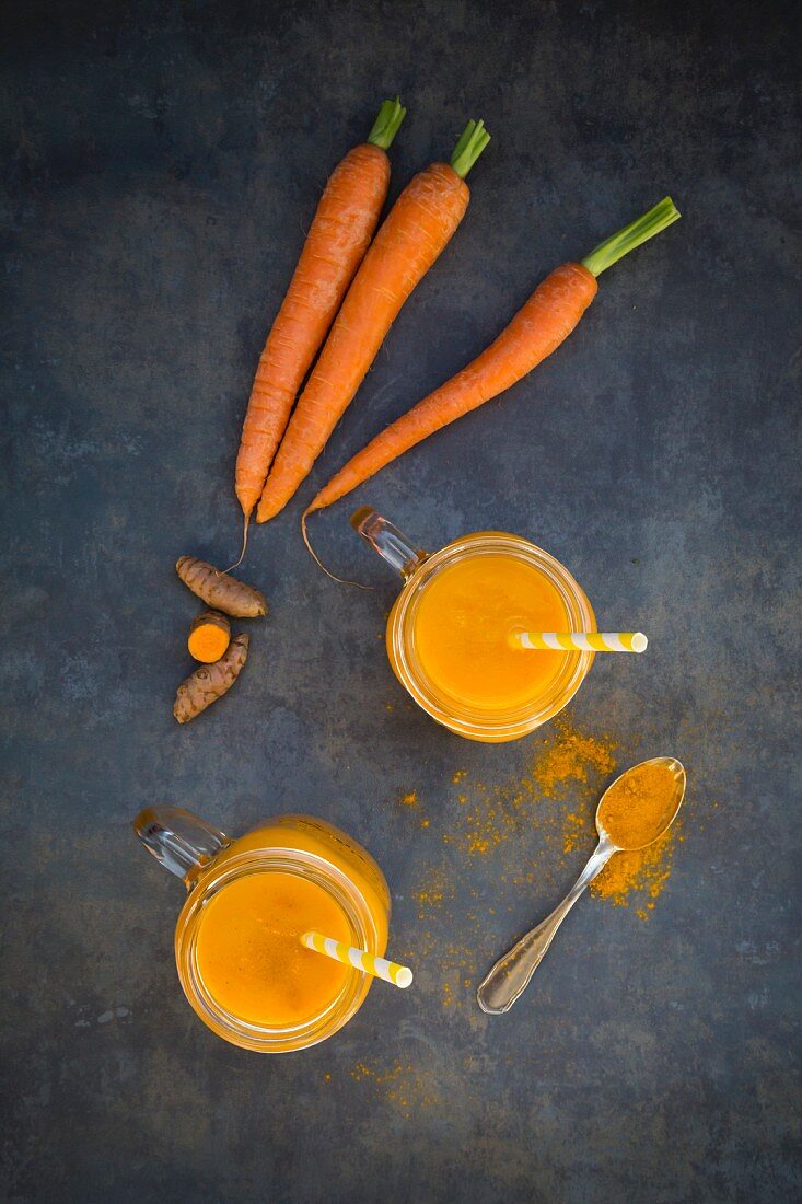 Karotten-Kurkuma-Smoothie in Gläsern mit Trinkhalm von oben