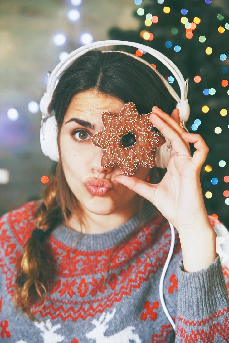 Frau mit Kopfhörer schaut durch ein Weihnachtsplätzchen