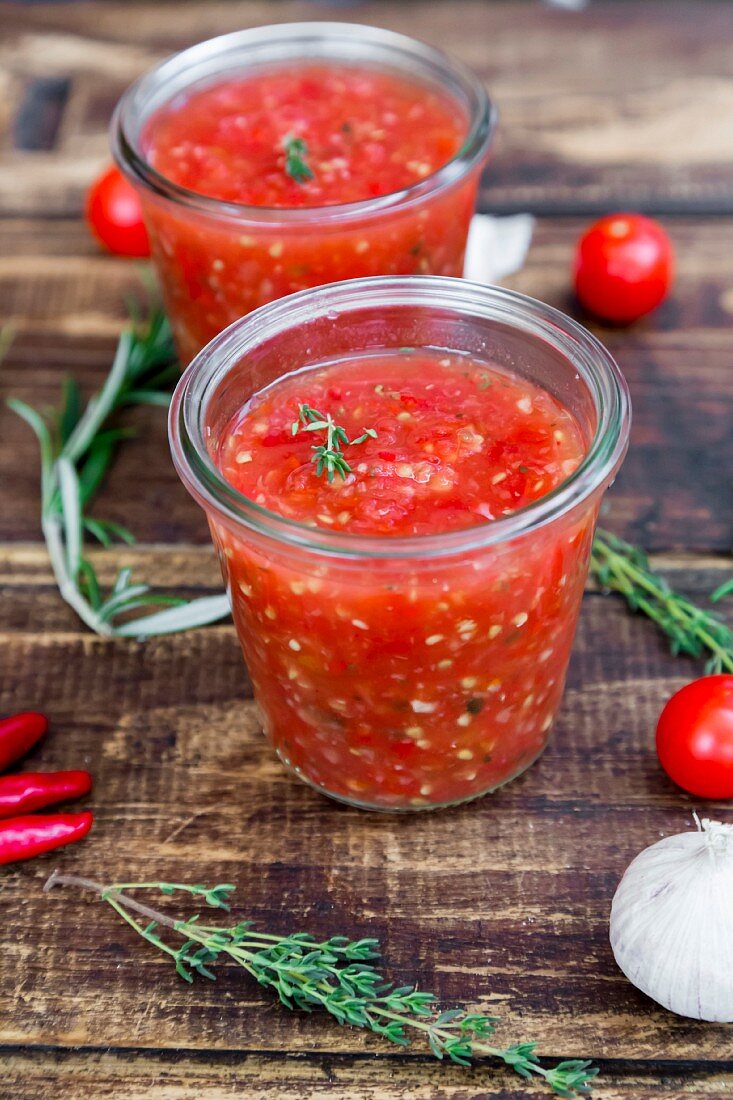 Selbstgemachte Tomatensauce und Zutaten auf Holzuntergrund