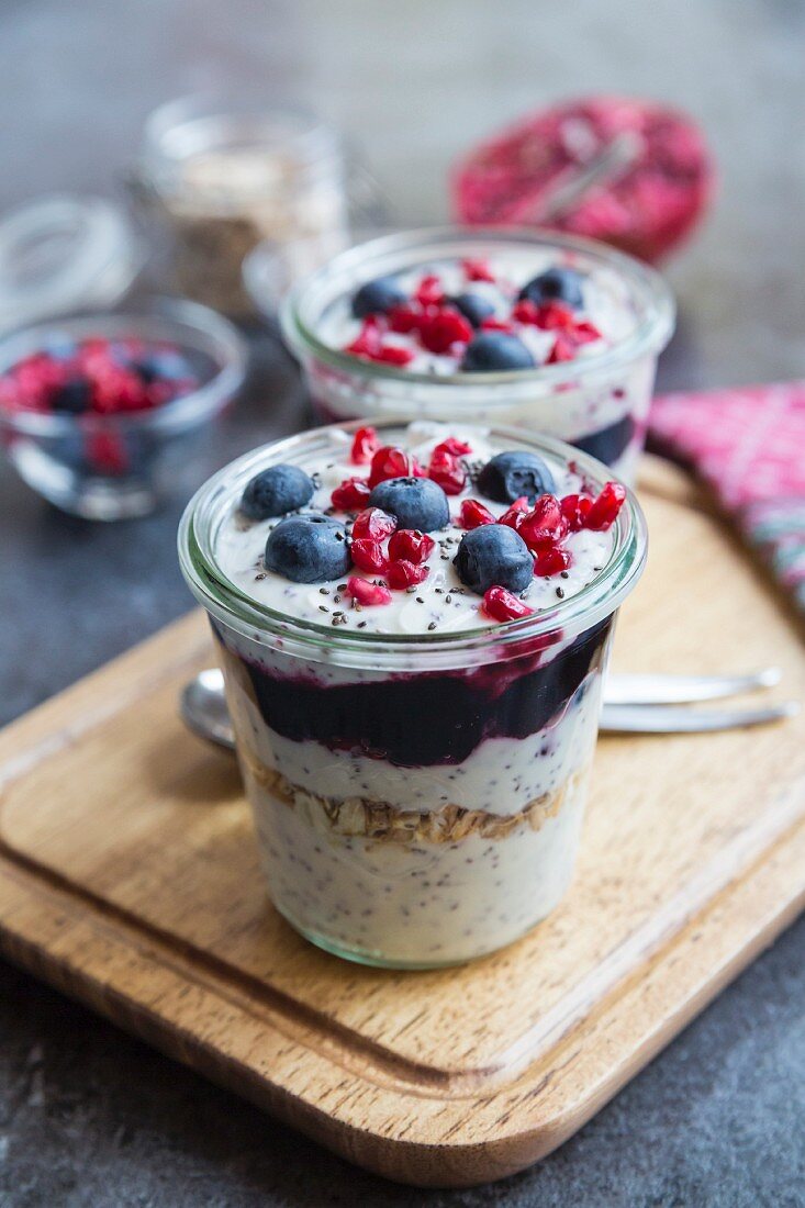 Joghurt mit Müsli, Blaubeermarmelade, Blaubeeren, Granatapfelkerne, Chiasamen im Glas