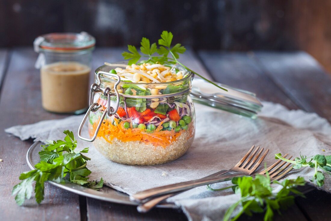 Regenbogen-Salat in einem Glas (Quinoa, Karotten, Erbsen, Rotkohl, Paprika und Mungobohnensprossen)