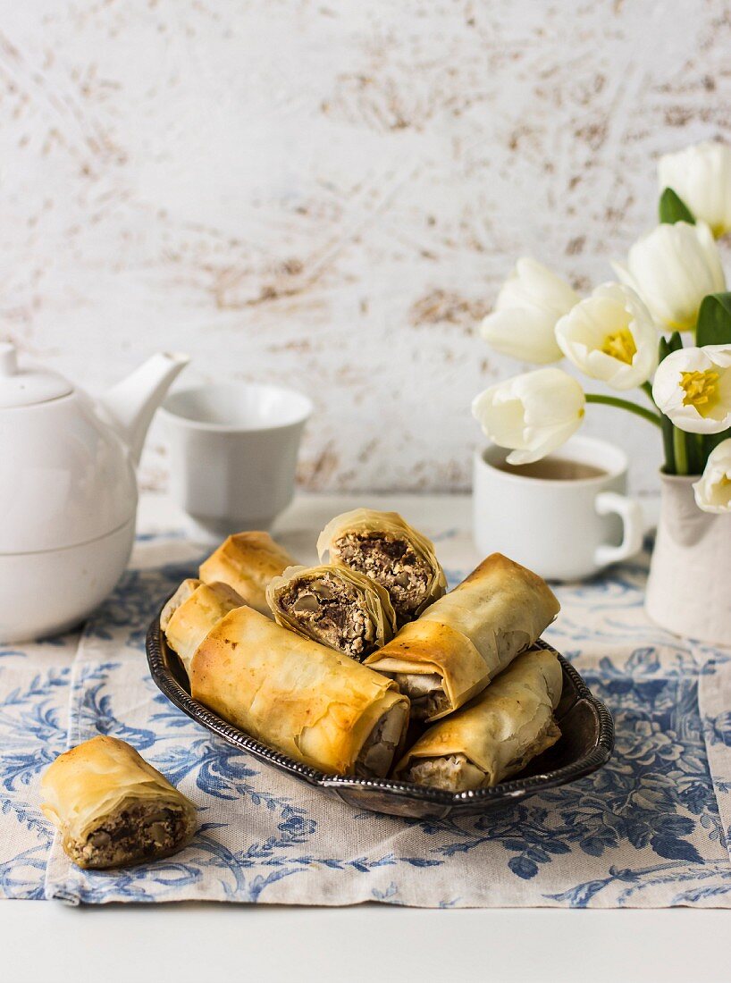 Filoröllchen mit Manouri-Käse, Walnüssen, Rosinen und Minze, Tee, weiße Tulpen