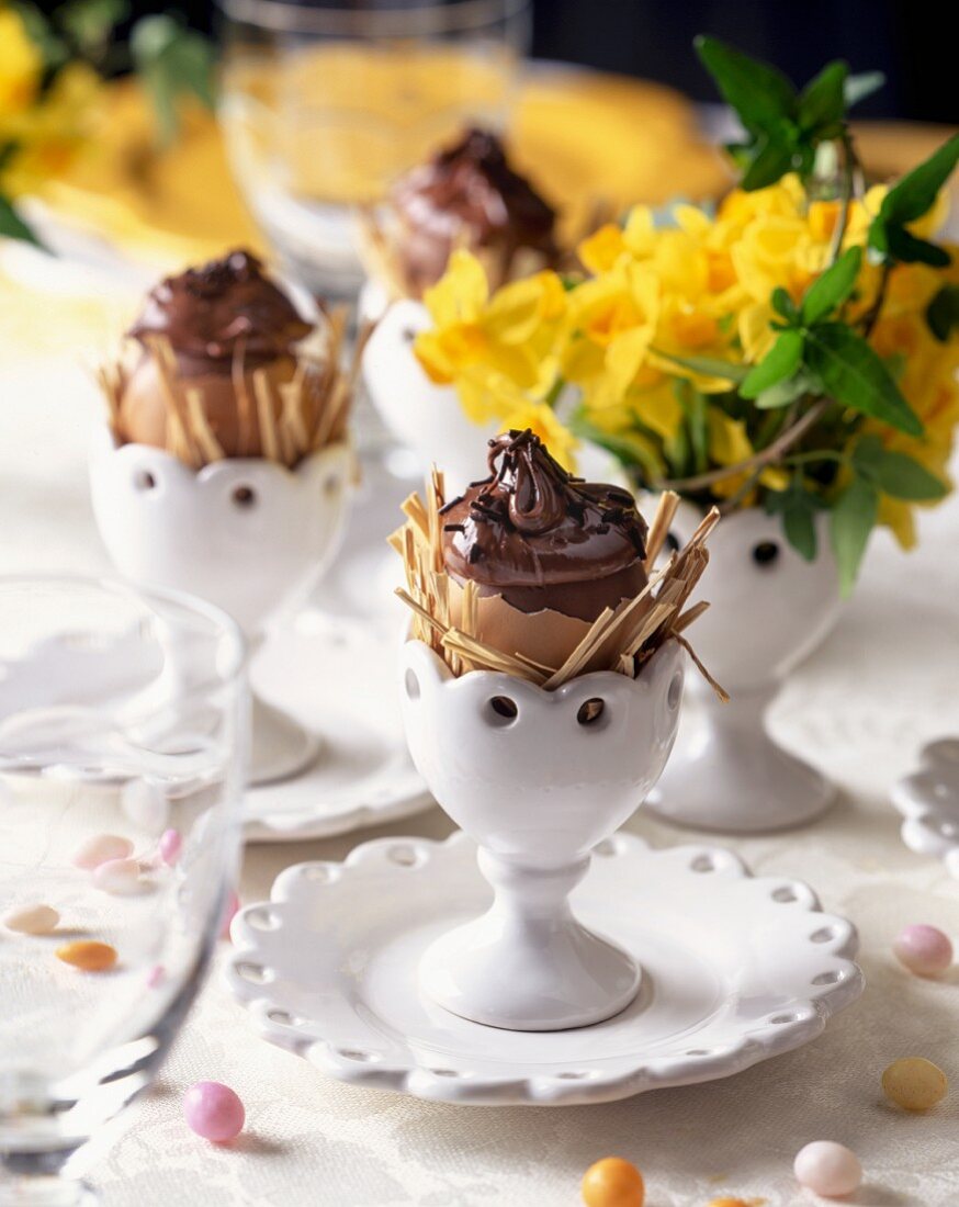 Chocolate eggs in egg cups on a table set for Easter